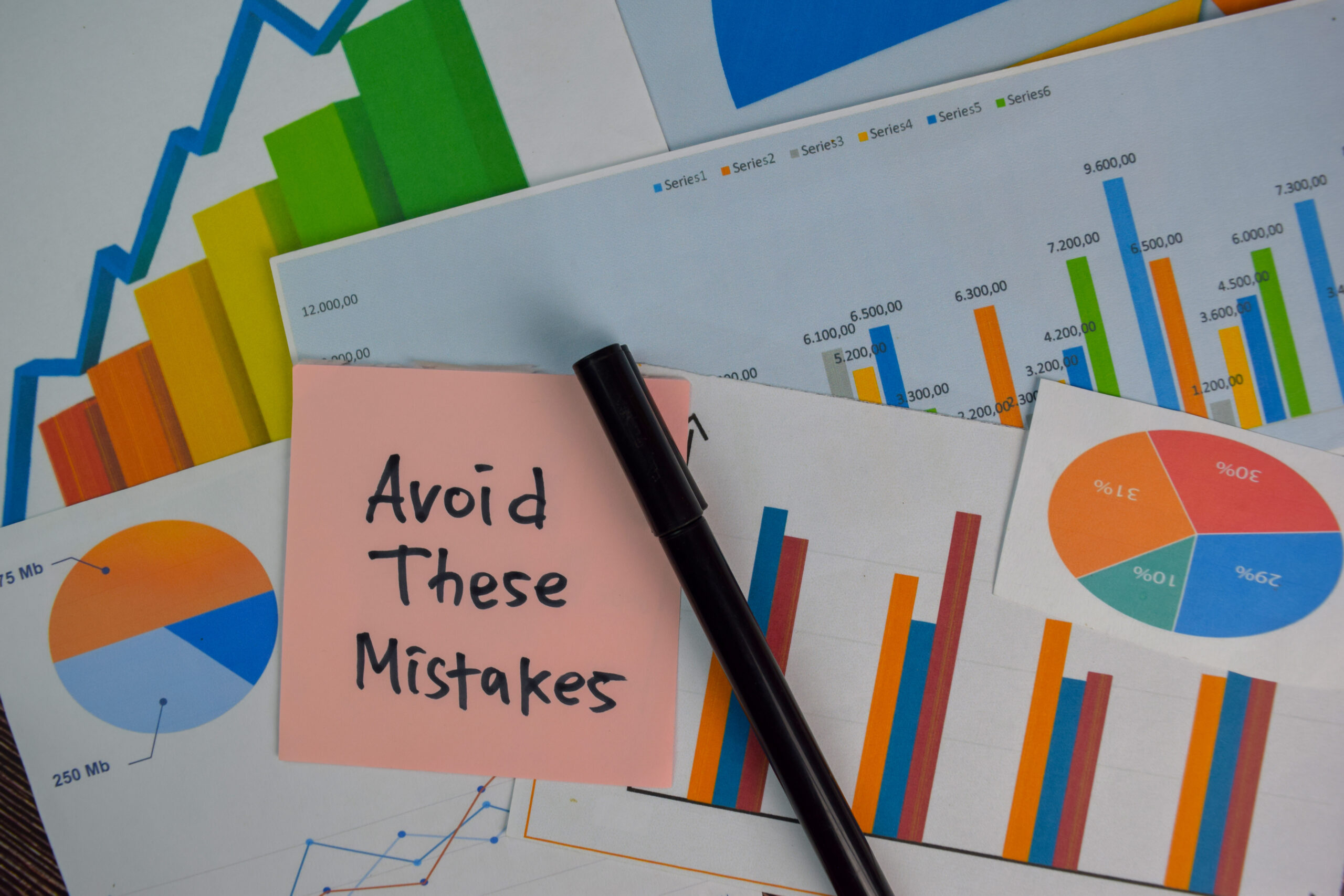 A sticky note with the words “Avoid These Mistakes” placed on top of business charts and graphs, symbolizing errors to avoid in job interviews and career growth.