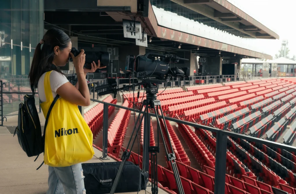 What Jobs Hire At 14 And 15 – young photographer using a camera at a sports venue, representing photography and event job opportunities for teenagers.